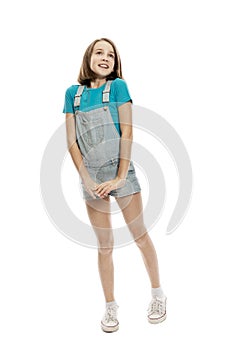 A teenager girl in denim overalls and a blue tank top emotionally jumps up. Isolated on a white background. Vertical