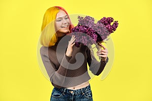 Teenager girl with dyed pink yellow hair holding lilac flowers in hands