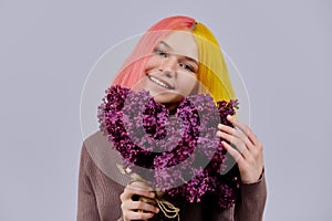 Teenager girl with dyed pink yellow hair holding lilac flowers in hands