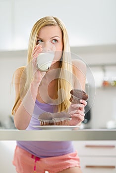 Teenager girl eating chocolate muffin with milk