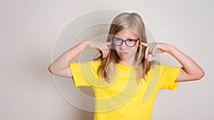 Teenager girl in eyeglasses closed her ears not to listen with c