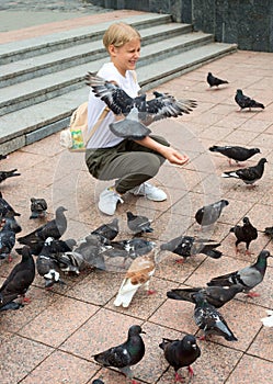 Teenager girl feeds the pigeons