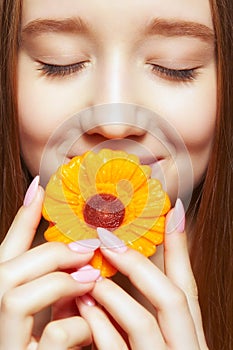 Teenager girl with  flower lollipop in hands closing mouth and smiling