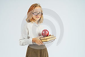 Teenager girl in glasses holding an apple and a book in her hands. Isolated background