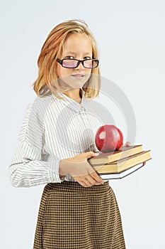 Teenager girl in glasses holding an apple and a book in her hands. Isolated background
