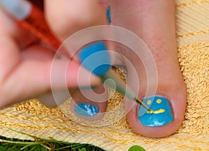 Teenager girl hand with enamel laque brush pedicure her toes foot