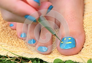 Teenager girl hand with enamel laque brush pedicure her toes foot