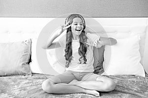 Teenager girl in headphones relax on bed at home using headphones, singing. Happy teen girl, positive and smiling