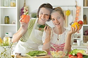 Teenager girl with her mother cooking together at kitchen table