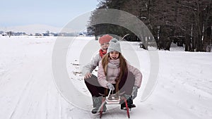 Teenager girl and her mother enjoying sleigh ride with their dog