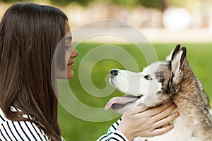 Teenager girl and her pet husky, portrait in the park. Friendship with a dog