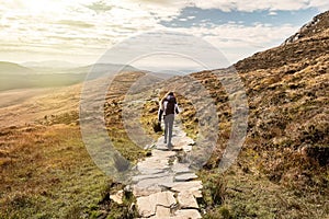 Teenager girl on a hike in a mountains. The model walks on a stone walk path. Letterfrack, Connemara National Park, county Galway