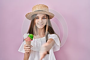 Teenager girl holding ice cream smiling friendly offering handshake as greeting and welcoming