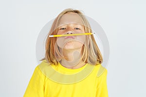 A teenager girl holds a pencil with her lips and nose - plays. Isolated background