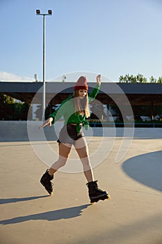 Teenager girl inline skating on boardwalk making stunt and tricks