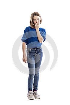 A teenager girl in jeans and a blue sweatshirt bites her nails. Full height. Isolated on a white background. Vertical