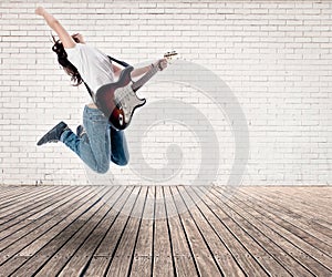 Teenager girl jumping with electric guitar