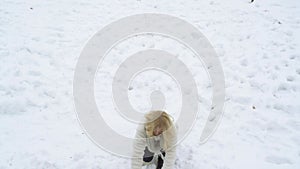 Teenager girl jumping and throwing a snowball. Young woman playing snow ball fight in winter. Girl in snow balls game