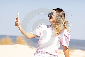 Teenager girl laughing in front of the smartphone on the Montevideo's Rambla