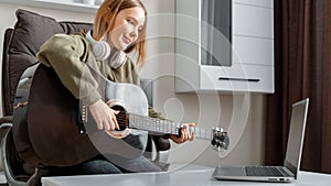 Teenager girl learning play guitar at home using online lessons. Hobby remote musical education acoustic guitar. Young