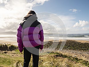 Teenager girl looking at Strandhill beach in county Sligo, Ireland. Warm sunny day, cloudy sky. Popular tourist area with stunning