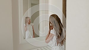 Teenager girl looking wet hair front mirror in bedroom. Young girl with wet hair after shower posing front bathroom in