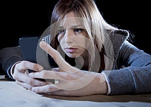 Teenager girl looking worried and desperate to mobile phone as internet stalked victim abused cyberbullying stress