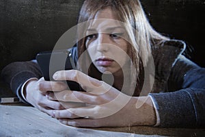 Teenager girl looking worried and desperate to mobile phone as internet stalked victim abused cyberbullying stress