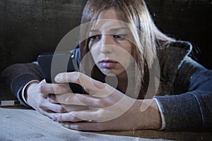 Teenager girl looking worried and desperate to mobile phone as internet stalked victim abused cyberbullying stress photo
