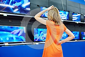 Teenager girl looks at LCD TVs in shop