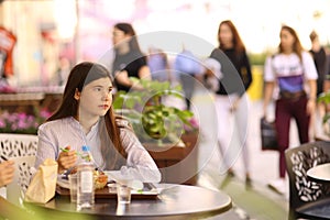 Teenager girl on lunch break sit in summer outdoor cafe