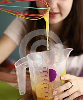 Teenager girl mix raw eggs in measure jar