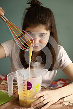 Teenager girl mix raw eggs in measure jar