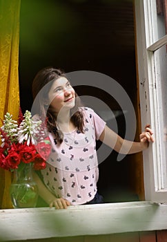 Teenager girl in pajama wake up open window with bouquet