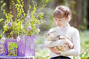 Teenager girl  play with real rabbit in the garden. Smiling child at Easter egg hunt with  pet bunny. Spring outdoor fun for kids