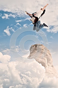 Teenager girl playing electric guitar and jumping