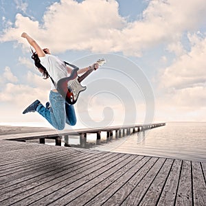 Teenager girl playing electric guitar on a wharf photo