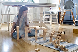 Teenager girl playing track constructor block tower with metallic ball Maria Montessori materials