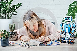 A teenager girl plugging cables to sensor chips while learning arduino coding and robotics