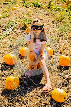 Teenager girl and pumpkin in the vegetable garden. A girl with a pumpkin wearing glasses for Halloween