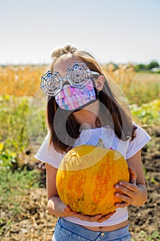 Teenager girl and pumpkin in the vegetable garden. halloween and girl in protective mask. Teenager girl and pumpkin