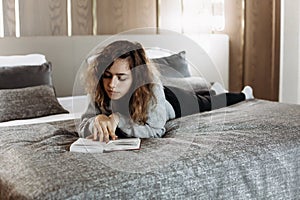 Teenager girl reading book on the bed