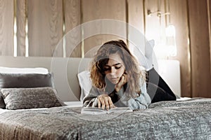 Teenager girl reading book on the bed