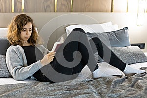 Teenager girl reading book on the bed