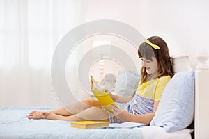 Teenager girl reading book in bed. Kids read