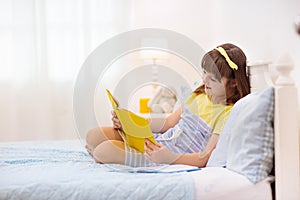 Teenager girl reading book in bed. Kids read