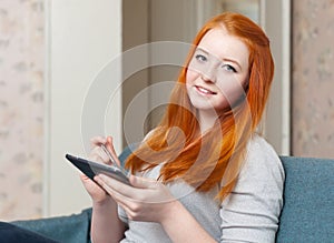 Teenager girl reads tablet computer at home