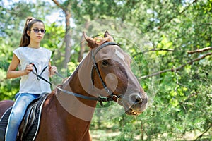 Teenager girl riding a brown horse, horseback riding for people in the park