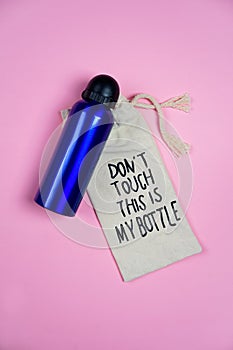 Teenager girl set blue bottle of water and tissue bag with lettering Don`t touch This is my bottle on light pink background