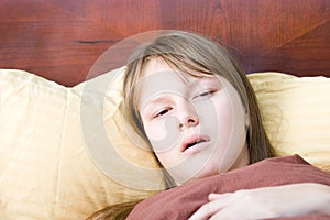 Teenager girl sick with flu lying in bed ill